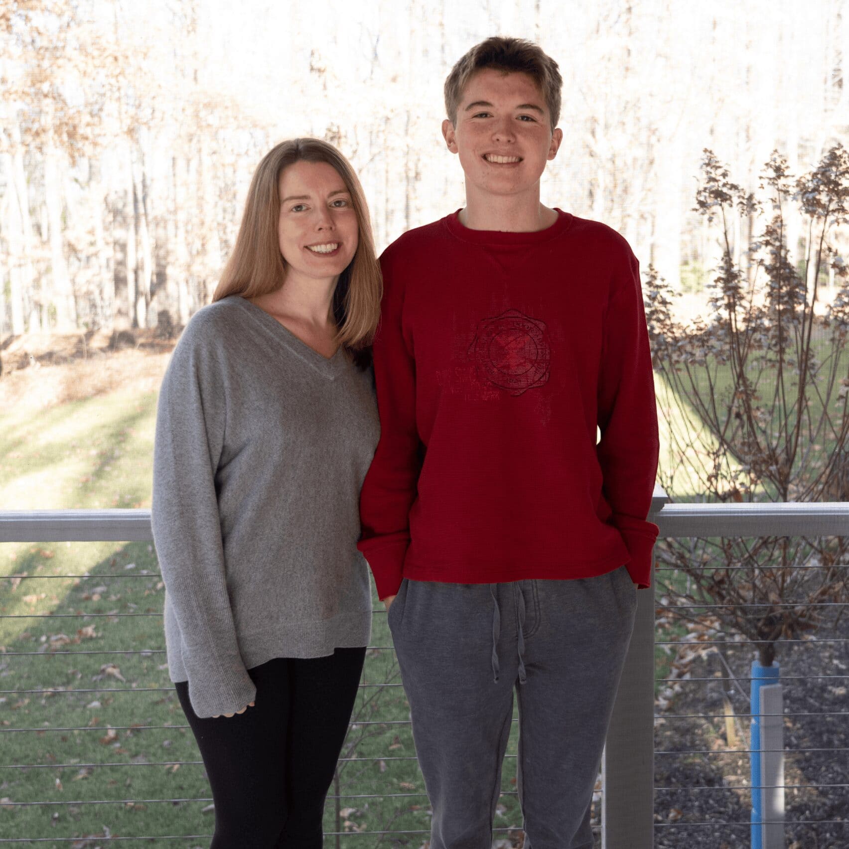 A man and woman stand together on a porch, enjoying a moment outdoors in a serene setting.