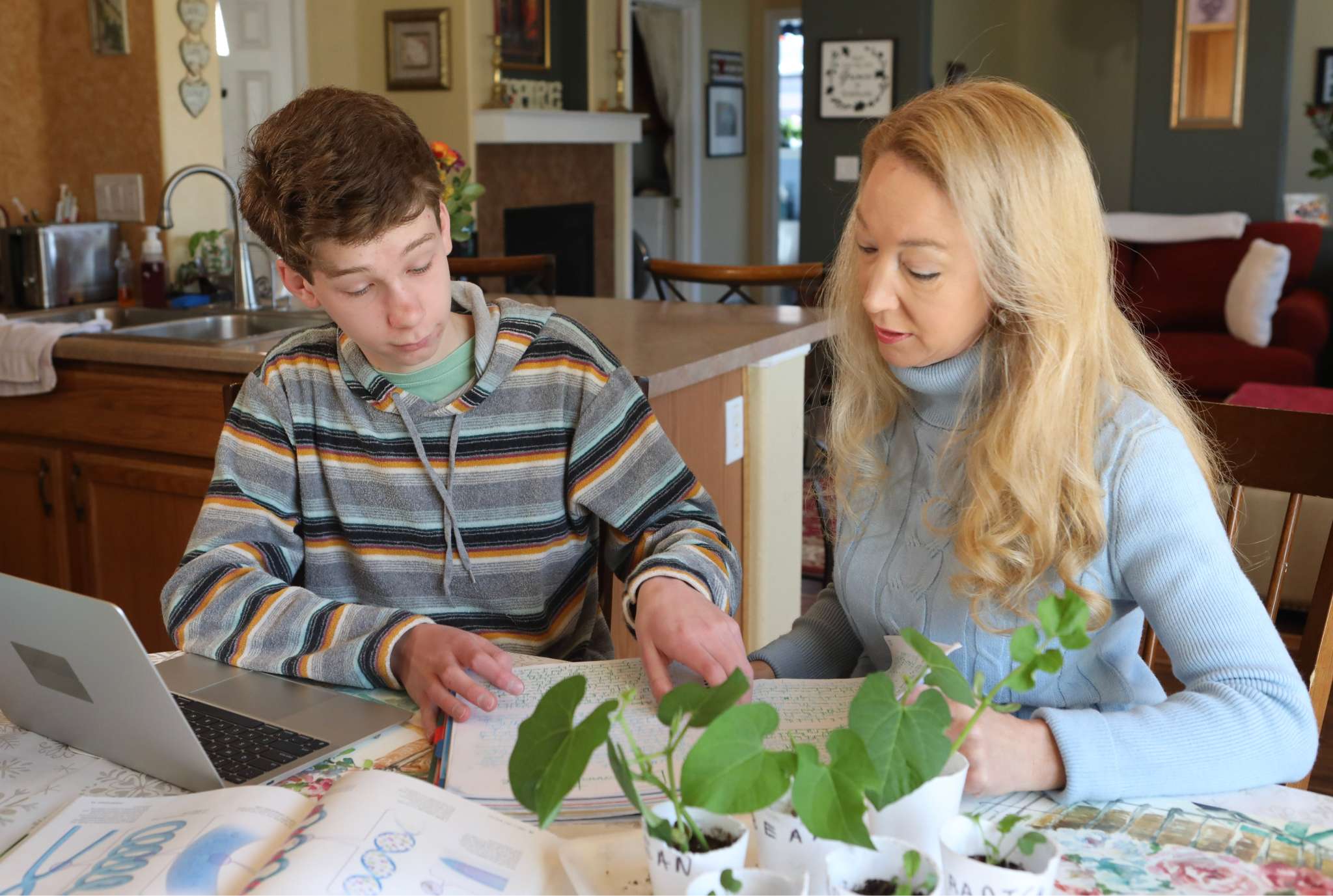 A woman and a boy collaborate on a laptop, focused on their task in a bright, engaging environment.