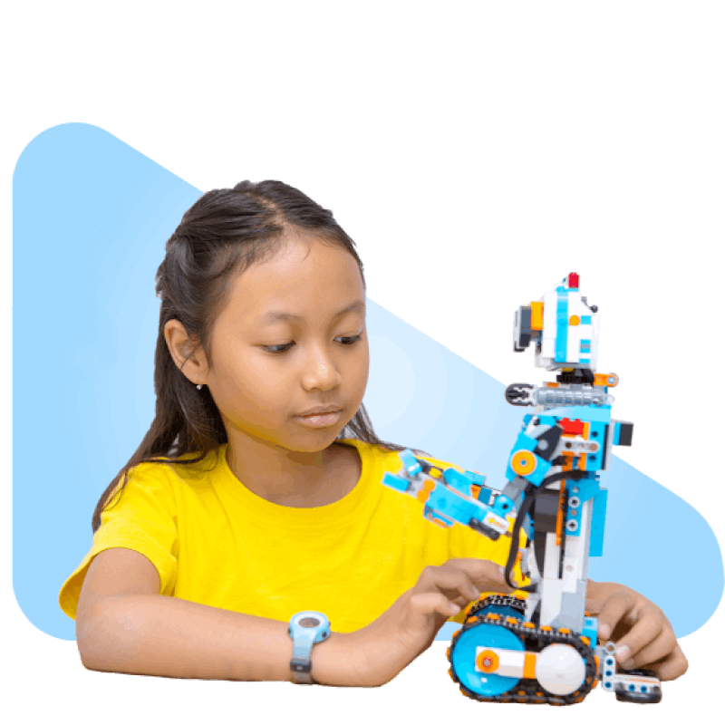 A young girl in a yellow shirt, focused and engaged, assembles a colorful blue and white robotic toy. The scene conveys creativity and learning.